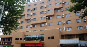 un grand bâtiment beige avec des fenêtres dans l'établissement GreenTree Inn Jiangsu Huaian Bus Terminal North Station Huaihai North Road Business Hotel, à Huai'an