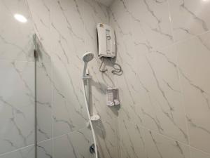 ein Bad mit einer Dusche und einem Haartrockner an der Wand in der Unterkunft Wan Residence Ratchatewi in Bangkok + 37 Fotos