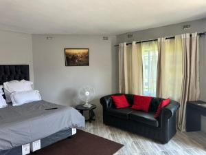 a bedroom with a bed and a couch at Staylax guesthouse in Harare
