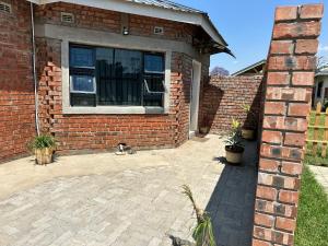 a brick house with a window and a cat sitting outside at Staylax guesthouse in Harare