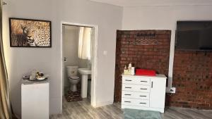 a bathroom with a white dresser and a brick wall at Staylax guesthouse in Harare +21 photos