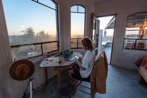 a woman sitting at a table in front of a laptop at Master Hexagon Bedroom 180 Ocean View in Todos Santos