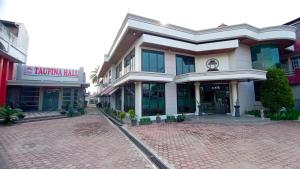 a building on a brick road in front of a building at Hotel Taufina Solok in Solok