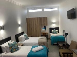 ein Hotelzimmer mit zwei Betten und einem Fernseher in der Unterkunft Juliet Rose Luxury Guesthouse B&B in Bloemfontein