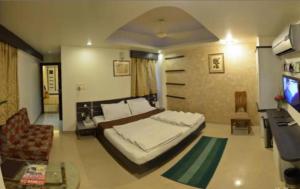 a bedroom with a bed and a couch and a television at Hotel Shree Vatika in Bhopal