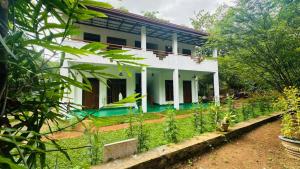 a white house with plants in front of it at The Secret Garden Sigiriya in Sigiriya