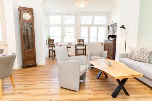 a living room with a table and chairs and a clock at Gulfhof Fresena in Norden