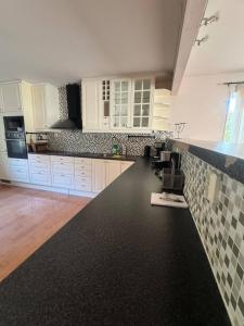 eine Küche mit weißen Schränken und einer schwarzen Arbeitsplatte in der Unterkunft Family & Worker Accommodations in Göteborg in Olofstorp