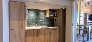 a kitchen with a sink and green tiles on the wall at Mitford Marula in Morganʼs Bay +7 photos