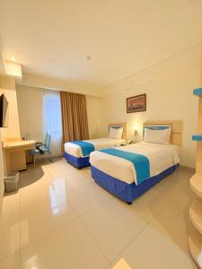 una habitación de hotel con dos camas y un escritorio en Hotel Brothers Solo, en Solo 64 fotos más