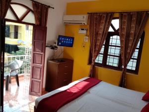 AguadaAlexmarie Guest house 5 min to candolim Beach的一间带床、电视和窗户的卧室