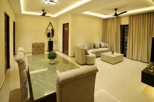 ein großes Wohnzimmer mit einem Glastisch und Stühlen in der Unterkunft La Coast Beach Villa ECR in Tirupporūr + 68 Fotos