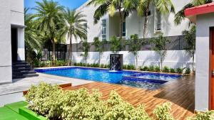 ein Swimmingpool vor einem Gebäude mit Palmen in der Unterkunft La Coast Beach Villa ECR in Tirupporūr