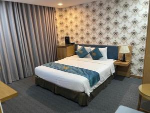 a hotel room with a large bed with blue pillows at The Blue Airport Hotel in Ho Chi Minh City