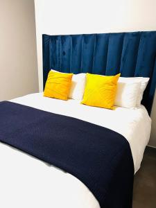 a bed with yellow pillows and a blue headboard at The Waterfall Nest 3 CB in Midrand