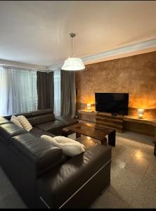 a living room with a leather couch and a flat screen tv at Koliba 222 in Bratislava