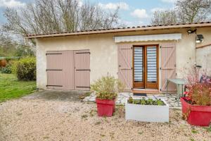 une petite maison avec deux portes de garage et deux plantes en pot dans l'établissement Studio Le Laurier, à Lherm