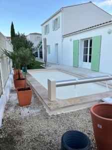 un patio devant une maison blanche avec des plantes dans l'établissement Villa les Mésanges 5 min from the beaches, à Vaux-sur-Mer