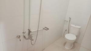a white bathroom with a toilet and a shower at Luxe5 Inn Hj Hasnah Hasan in Takengon