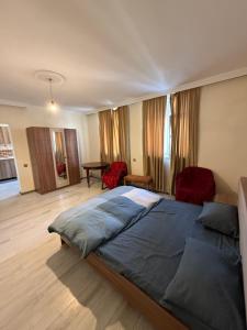 1 dormitorio con 1 cama grande y 2 sillas rojas en Rova Hostel, en Baku
