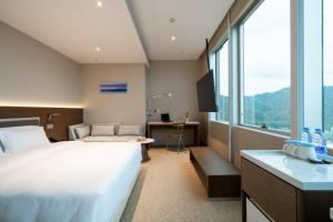 a bedroom with a bed and a desk and a window at Calmsea Hotel in Shenzhen