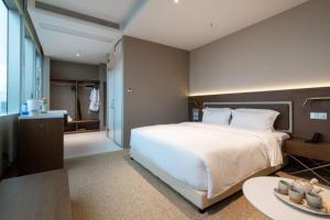 a bedroom with a large white bed and a table at Calmsea Hotel in Shenzhen