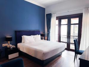 a bedroom with a large bed and a blue wall at TTC Hotel - Hoi An in Hoi An +87 photos