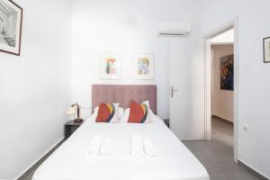 a white bedroom with a large white bed with pillows at Renovated 4 Bdr House near Acropolis - New Beds, Terrace & Green Yard in Athens