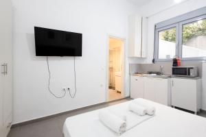 a white kitchen with a tv on a wall at Renovated 4 Bdr House near Acropolis - New Beds, Terrace & Green Yard in Athens
