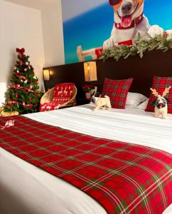 Ein Hund sitzt auf einem Bett mit einem Weihnachtsbaum. in der Unterkunft The Originals City, Hotel Cap Maya, Cap d'Agde in Cap d'Agde