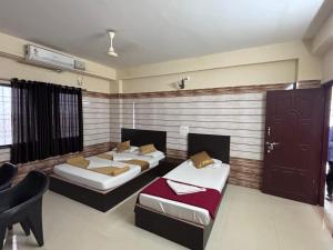 una habitación con dos camas y una mesa y sillas en Yammuna Vihaar Tourist Home, en Kollūru