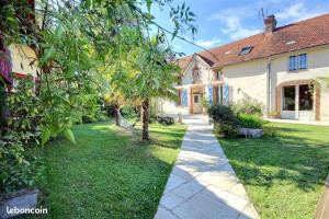 un jardin d'une maison avec un trottoir dans l'établissement Le Clos Fleuri, à Pontiacq-Viellepinte