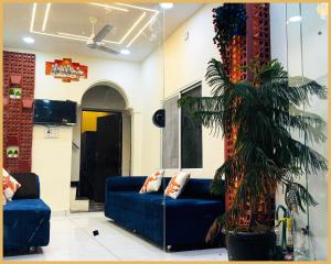 a living room with a blue couch and a palm tree at Hotel Shree- Nidhi Premium comfort # Stay Near Mahakaleshwar Jyotirlinga # Railway Station # Free Wi-Fi And Parking Service - Best Hotel In Ujjain in Ujjain