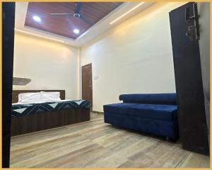 a room with a bed and a blue couch at Hotel Shree- Nidhi Premium comfort # Stay Near Mahakaleshwar Jyotirlinga # Railway Station # Free Wi-Fi And Parking Service - Best Hotel In Ujjain in Ujjain +2 photos