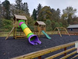 a playground with two swings and a slide at Barrhill Holiday Park - Glamping in South West Scotland - Stinchar in Girvan