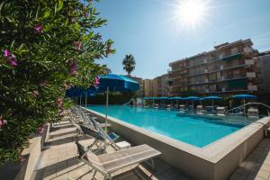 a swimming pool with chairs and umbrellas next to a building at Perla Marina Apartments in Pietra Ligure