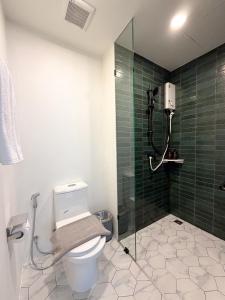 a bathroom with a shower and a toilet and green tiles at Laoteng Boutique Hotel in Phuket Town