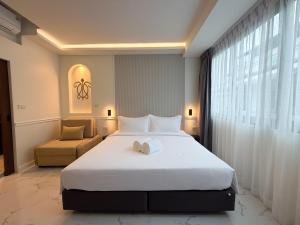 a bedroom with a large white bed and a chair at Laoteng Boutique Hotel in Phuket Town