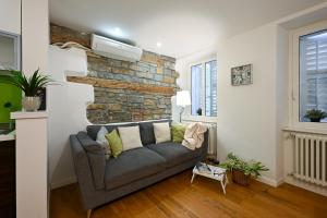 a living room with a couch and a brick wall at La Tana di Alice in Muggia +11 photos