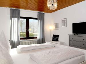 a white bedroom with a large bed and a window at Fewo Wrede am Sauerland-Radring in Wenholthausen