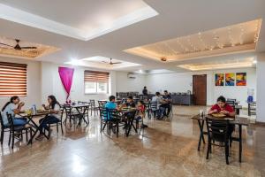 un groupe de personnes assises à des tables dans un restaurant dans l'établissement FabHotel The Grace Inn Near Galleria Market & Golf Course Road, à Gurgaon
