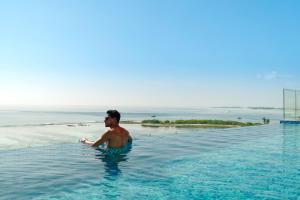 un hombre parado en el agua en una piscina en h78 Guraidhoo, en Guraidhoo