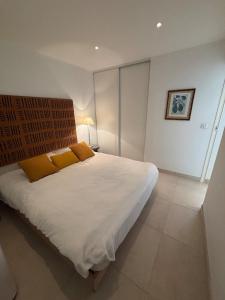 Un dormitorio con una gran cama blanca con almohadas naranjas. en Magnifique appartement vue mer Sanary-sur-mer, en Sanary-sur-Mer