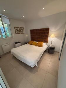 Un dormitorio con una gran cama blanca con almohadas amarillas. en Magnifique appartement vue mer Sanary-sur-mer, en Sanary-sur-Mer