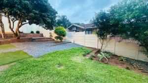 een achtertuin met een wit hek en een grasveld bij Melodia V in Durban