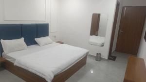 een slaapkamer met een bed met een blauw hoofdeinde bij Hotel Ashoka in Karnāl