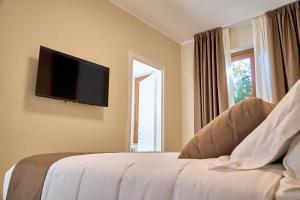 une chambre avec un lit avec une télévision à écran plat au mur dans l'établissement Guest House Aura - Lumys Fiumicino, à Isola Sacra