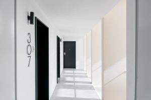 un corridoio con pareti bianche, pavimenti bianchi e porte nere di GuestReady - Central Premium Studio - Aveiro ad Aveiro