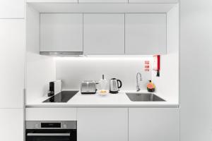 una cucina bianca con mobili bianchi e un lavello di GuestReady - Central Premium Studio - Aveiro ad Aveiro