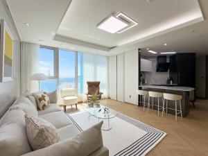 Una sala de estar con un sofá blanco y una cocina. en Brown Suites Busan Station, en Busan